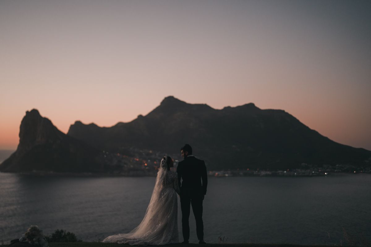 Wedding couple silhouetted against a sweeping sunset sky in the Western Cape